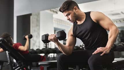 junger, athletischer Mann trainiert seinen Bizeps im Gym
