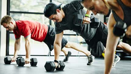 Group of friends doing pushups with dumbbells