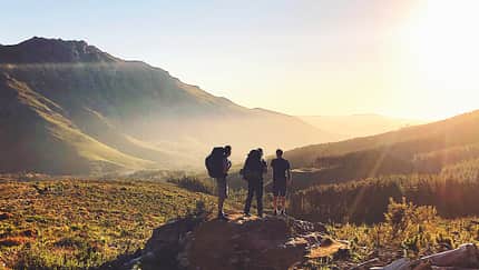 Rearview of Hikers with backpacks enjoying the sunset in the mountains