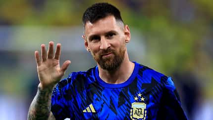 Lionel Messi winkt auf dem Fußballfeld im Fußballtrikot in die Kamera