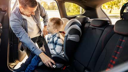 Vater setzt sein Kind in den Kindersitz