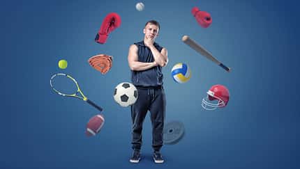 A,Thoughtful,Muscular,Man,Stands,Surrounded,By,Different,Sport,Gear