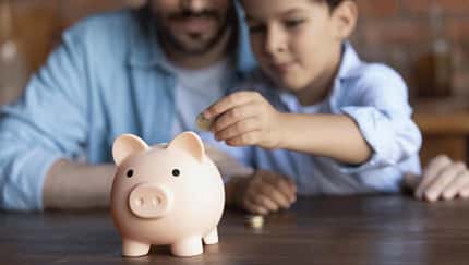 Vater und Sohn stecken Geld in ein Sparschwein