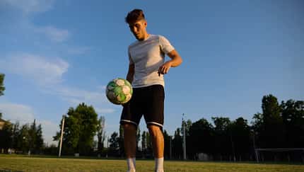 Professional,Footballer,Juggling,Soccer,Ball,On,Stadium,At,Sunset.,Young