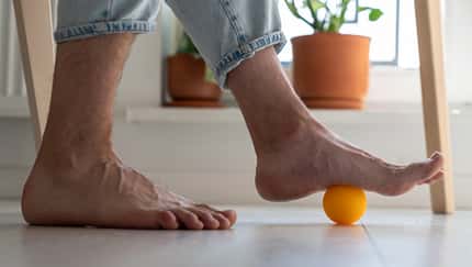 Mann rollt über Faszienball mit Füßen