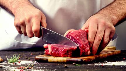 Mann schneidet rohes Rindfleisch