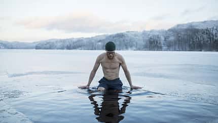 Man swimming in frozen lake