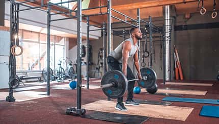 Black Male Muscular Athlete Practicing Deadlift with Barbell