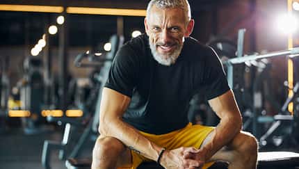 Sportsman with a happy smile sitting on the weight bench