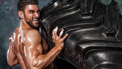 Ein muskulöser Mann stemmt einen Reifen beim Krafttraining