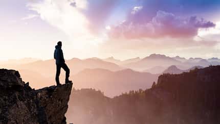 ein wandernder Mann steht auf einem Berggipfel