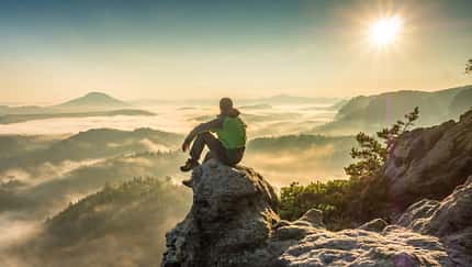 Die Silhouette eines Mannes beim Wandern auf dem Bergrücken auf dem Gipfel der Wolken