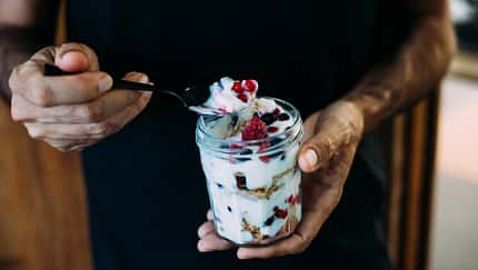 Ein Mann hält ein Glas mit Quark und gefrorenen Beeren