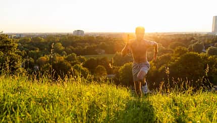 Mann rennt bei Sonnenuntergang über eine Wiese