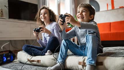 Zwei Kinder sitzen vor einem Fernseher und daddeln