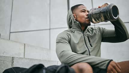 Junger, sportlicher Mann trinkt aus Wasserflasche in Sportkleidung