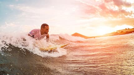 Male athlete surfing at sunset - Surfer man performing outdoor inside ocean- Extreme sport, competition, travel and summer vacation concept - Soft focus on man head