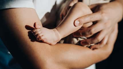 Close up of a loving young Asian father carrying his newborn baby daughter in arms. Bonding moment of father and daughter. Fatherhood. Skin to skin contact. Love, care and tenderness