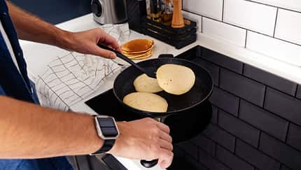 Mann brät Pancakes in der Pfanne