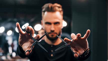 Mann mit Schere vor dem Gesicht