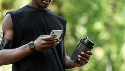 Mann hält einen Shaker in der Hand und schaut auf sein Handy