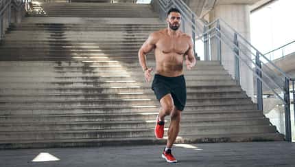 Mann joggt oberkörperfrei eine Treppe runter