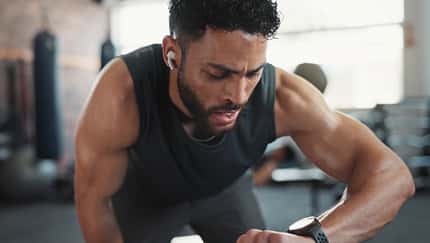 Ein Mann in Sportkleidung schaut auf seine Fitnessuhr