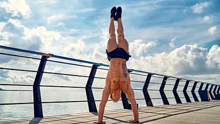 Ein trainierter Mann macht einen Handstand auf einem Schiffsdeck