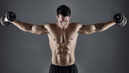 Young athletic male bodybuilder lifting dumbbells