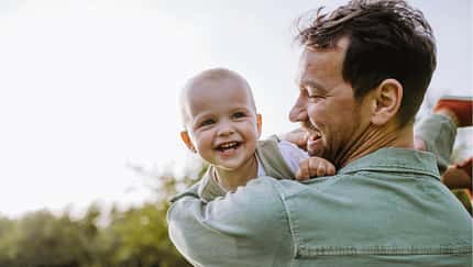 Ein Vater trägt sein glückliches Baby auf dem Arm