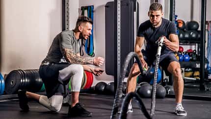 Ein Mann trainiert mit einem Trainer an den Battle Ropes
