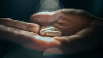 Hände, die Kapseln an Nahrungsergänzungsmitteln halten