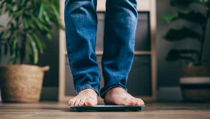 A man with dry winter feet weighs himself on a bathroom scale. A man with dry winter feet weighs himself on a bathroom scale.