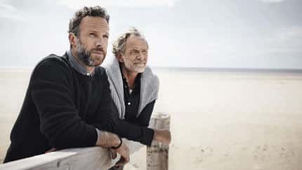 Ein Vater und sein erwachsener Sohn schauen aufs Meer