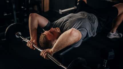 Ein Mann auf einer Hantelbank, der eine Trizeps-Übung durchführt Ein Mann auf einer Hantelbank, der eine Trizeps-Übung durchführt