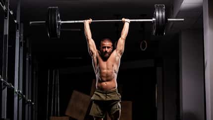 Ein Mann mit einer Langhantel über dem Kopf beim Schulterdrücken