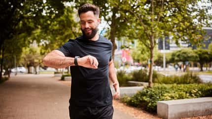 Ein Mann geht joggen und schaut dabei auf seinen Fitness-Tracker Ein Mann geht joggen und schaut dabei auf seinen Fitness-Tracker