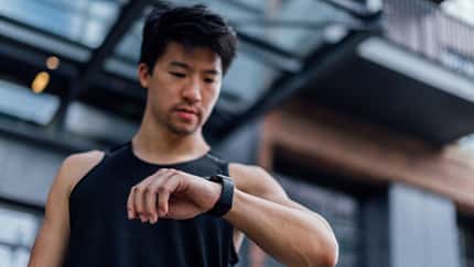 Ein Mann schaut beim Training auf seine Fitnessuhr Ein Mann schaut beim Training auf seine Fitnessuhr