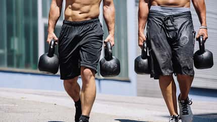 Männer machen den Farmers Walk mit Kettlebells