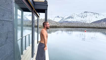 Man relaxing on sauna dock and contemplating the fjord view