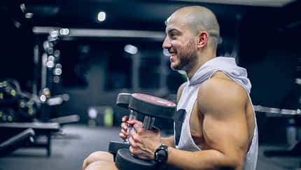 Ein starker Mann mit Handtuch über den Schultern und Kurzhanteln in den Händen Ein starker Mann mit Handtuch über den Schultern und Kurzhanteln in den Händen