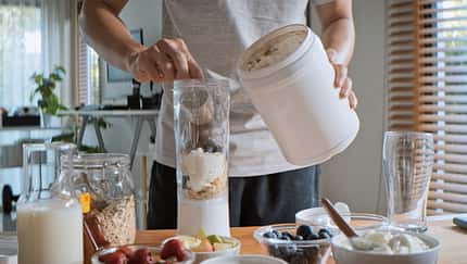 Young adult Asian man prepare and make protein shake drink, mixed fruit cereal juice, using blender mixer. Fitness dietary activity, healthy diet lifestyle, health care nutrition concept