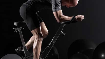 Man cycling on exercise bike, side view