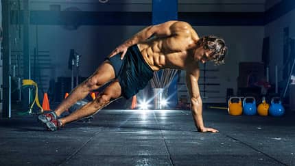 Muskolöser Mann in Site Plank Position in dunklem Gym Muskolöser Mann in Site Plank Position in dunklem Gym