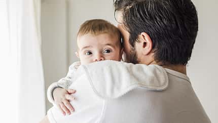 Ein Vater hält einen Säugling im Arm