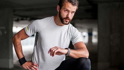 Mann macht eine Trainingspause und blickt auf seine Smartwatch.