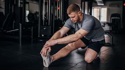 Mann dehnt seine Beinmuskulatur nach dem Training im Fitnessstudio. Mann dehnt seine Beinmuskulatur nach dem Training im Fitnessstudio.