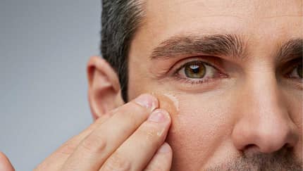 Closeup: Mann trägt Creme im Gesicht auf 