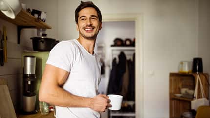 Young man in kitchen with coffee