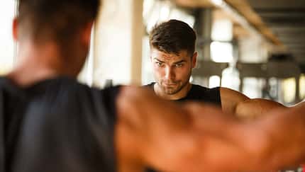 Ein junger Mann schaut sich beim Training im Fitnessstudio im Spiegel an